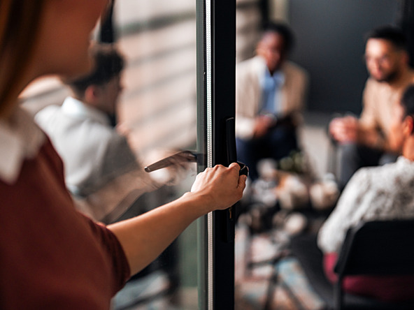 woman walking into room of people having discussion